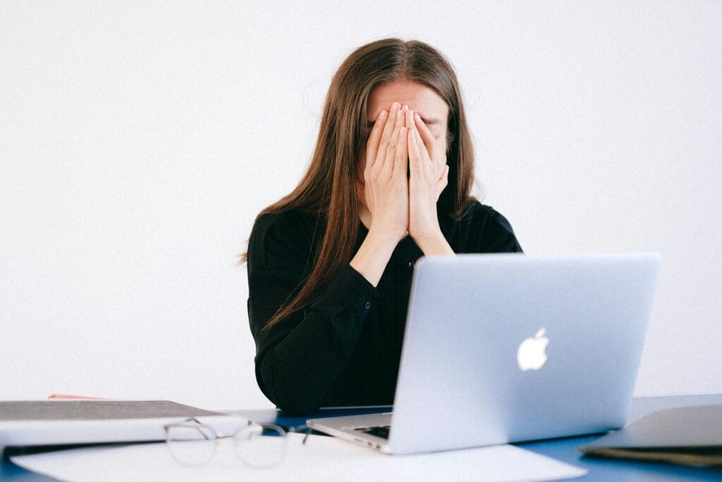 Anti anxiety Woman feeling stressed and overwhelmed at her desk while working remotely on a laptop.